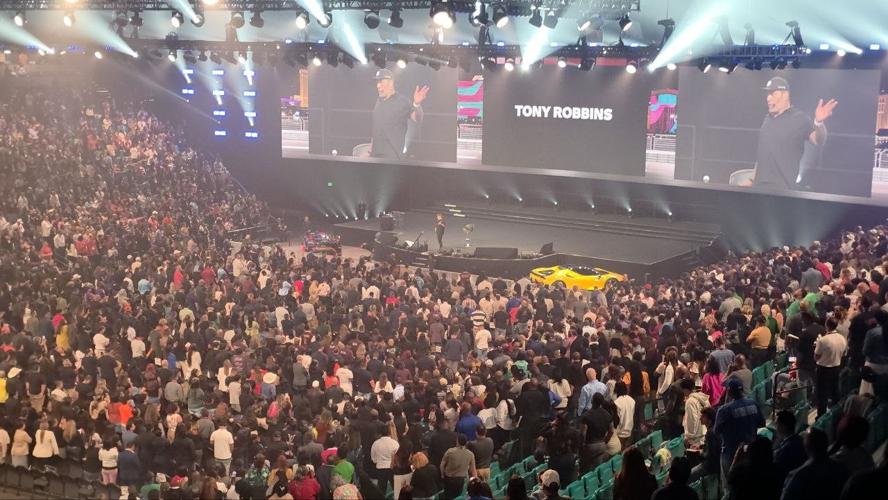 Tony Robbins presenting on the main stage at PHP Lights Out 2026, his name displayed on the arena screens