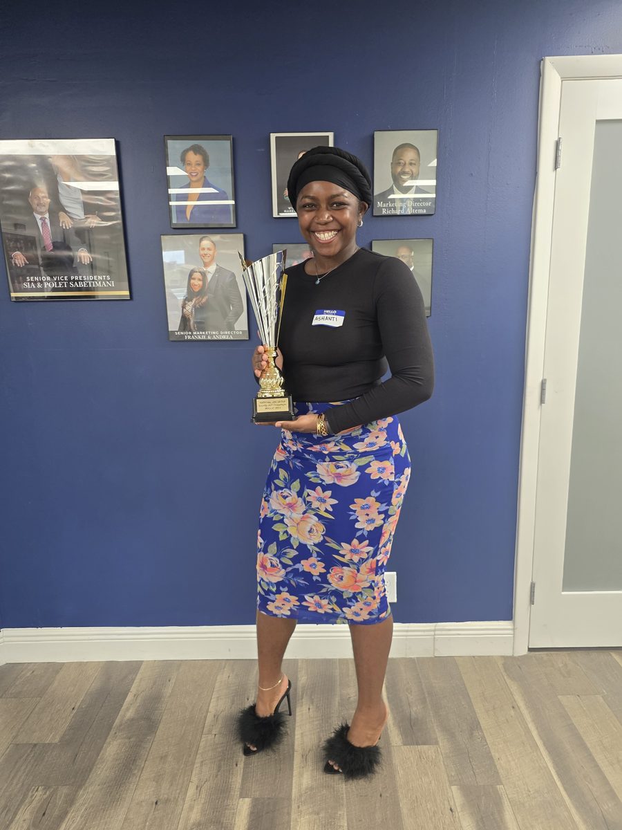 A BTT team member holding the National Life Group Lights Out Champion trophy at the leadership wall