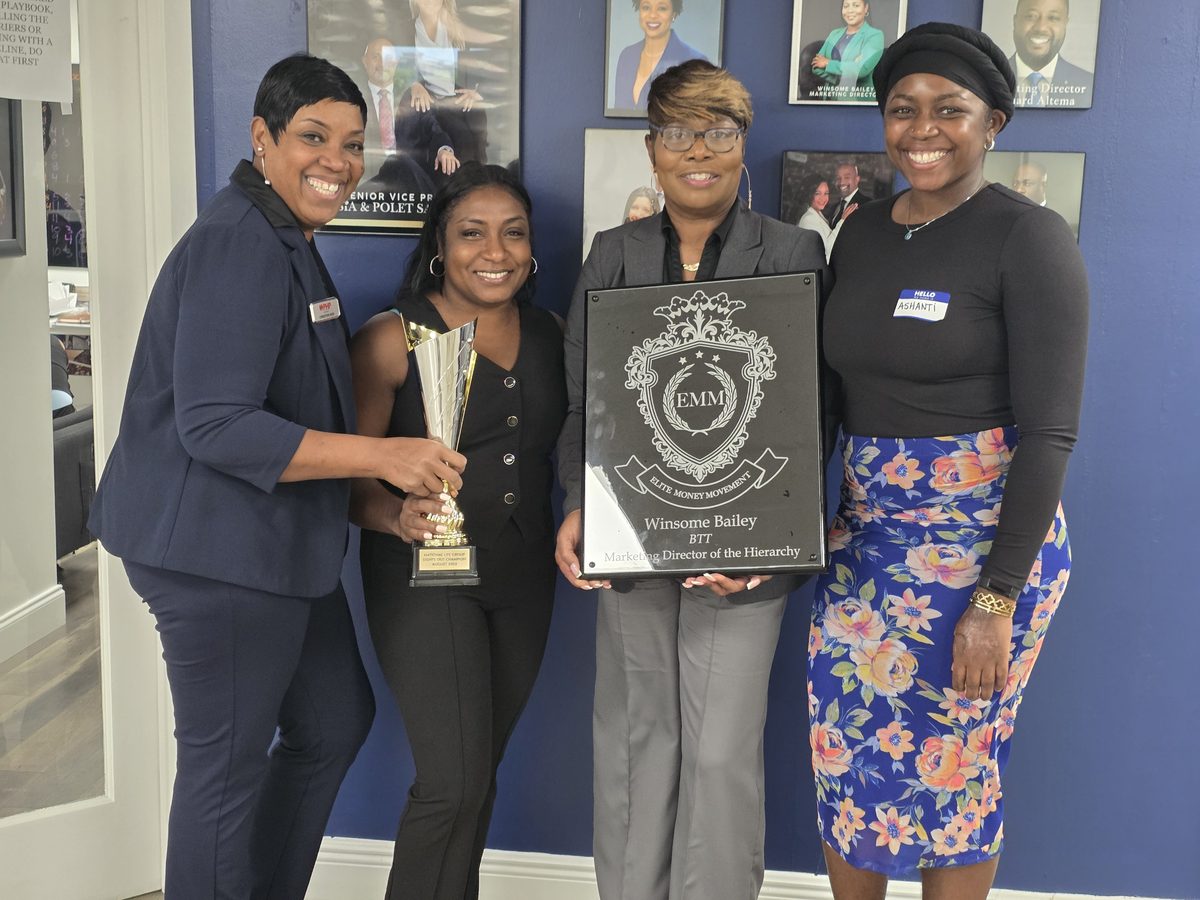 Four BTT team members holding the Elite Money Movement plaque and the Lights Out Champion trophy