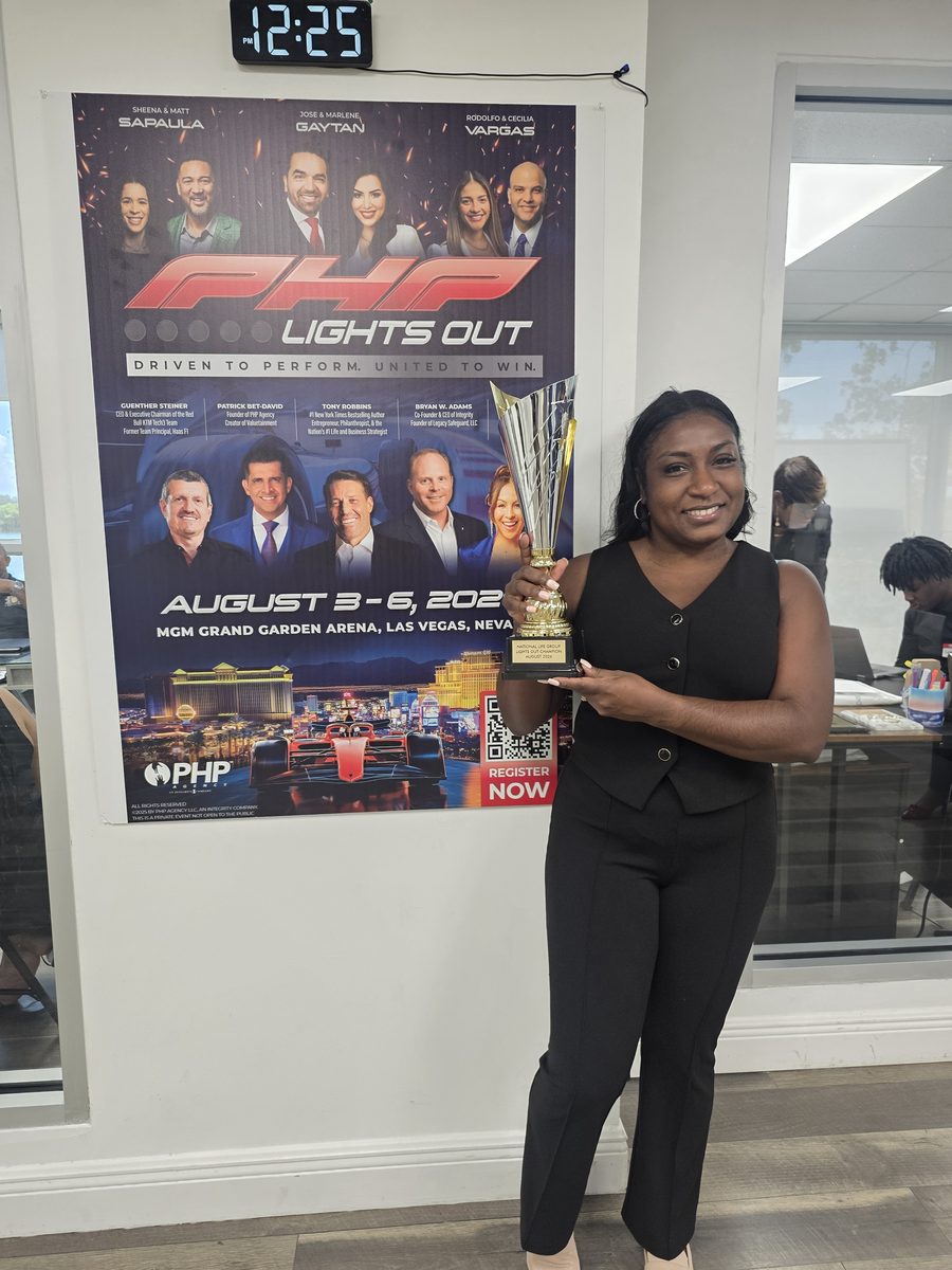 A BTT team member holding the Lights Out Champion trophy beside the PHP Lights Out event poster